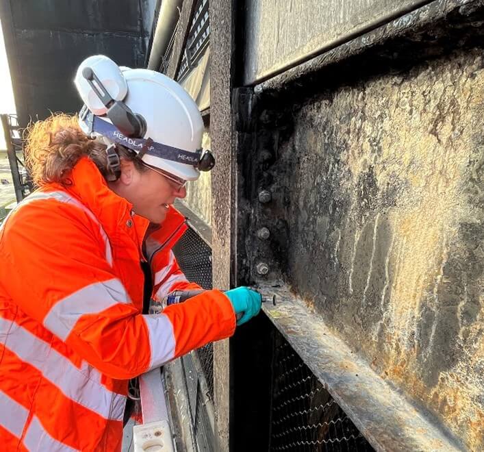 Image of materials expert Philippa Moore sampling the microstructure of a fire-blackened steel beam