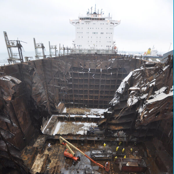 inside of a cargo ship that has been on fire as workers clear through debris